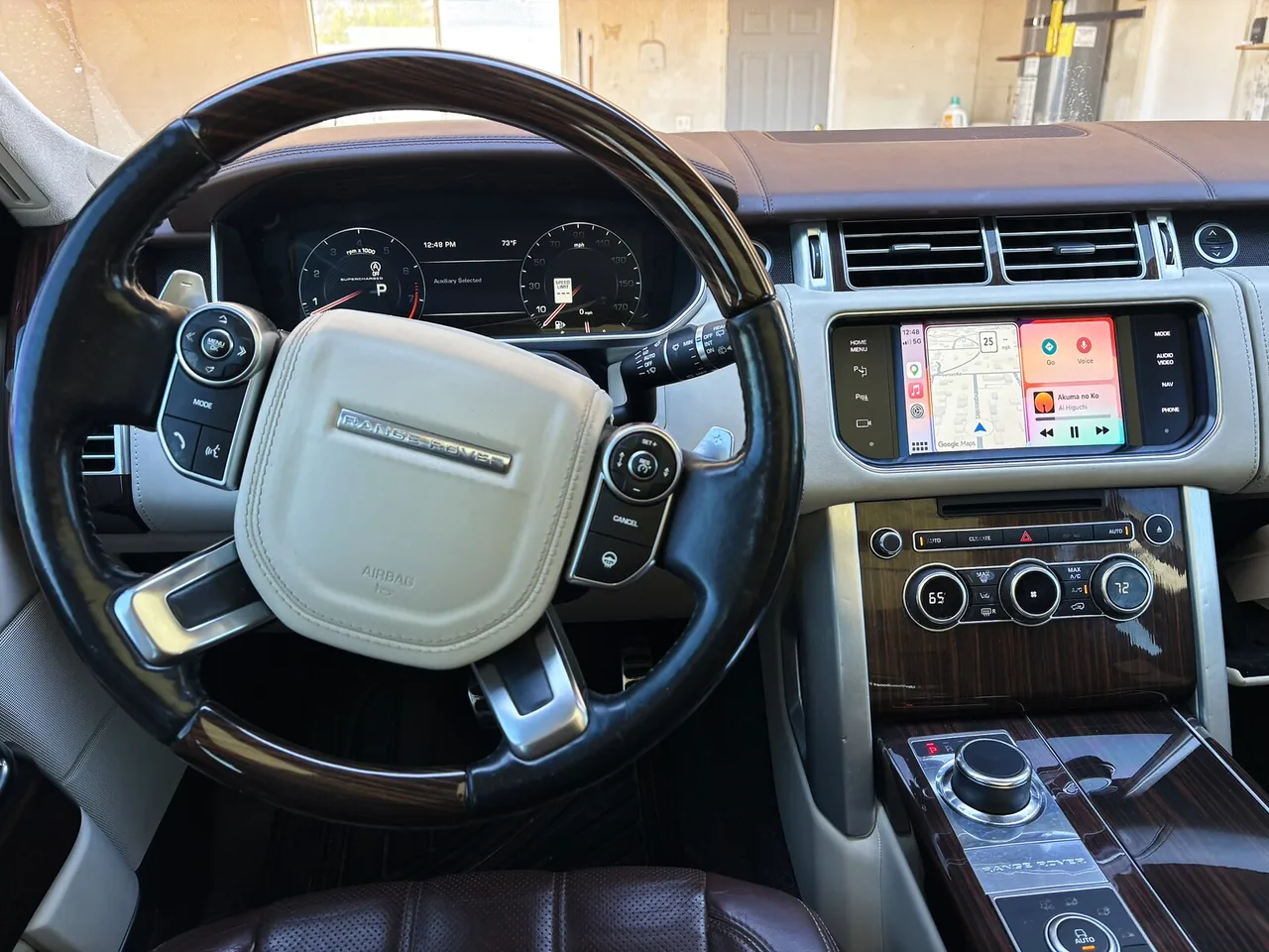 Driver's-seat view of the Range Rover cabin, with the CarPlay dashboard showing maps and music on the original display